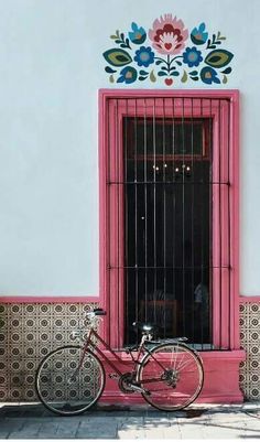 a bike parked in front of a window with bars on the windowsill and flowers painted on the wall