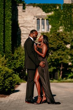 a man and woman standing next to each other in front of a building with trees