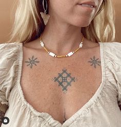 a woman with tattoos on her chest looking at the camera