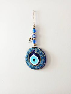 a blue evil eye pendant hangs on a white wall