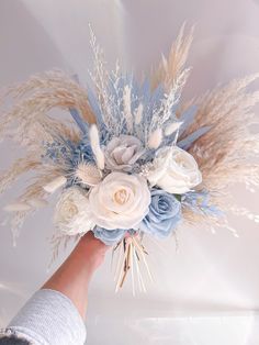 a hand holding a bouquet with flowers and feathers