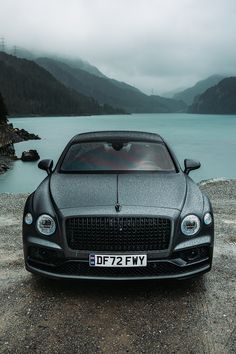 a black car parked on the side of a lake