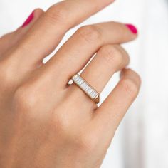 a woman's hand wearing a gold and white ring with a bar on it