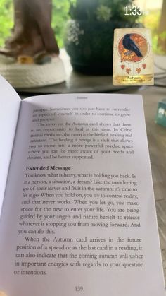 an open book sitting on top of a wooden table next to a person's foot