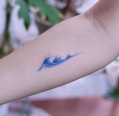 a woman's arm with a blue wave tattoo on the left side of her arm