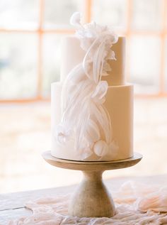 a three tiered white wedding cake sitting on top of a table