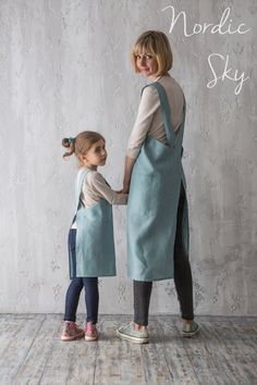 a woman and child standing next to each other in front of a wall with white paint