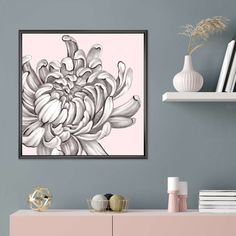 a pink and white flower is hanging on the wall above a dresser in a living room