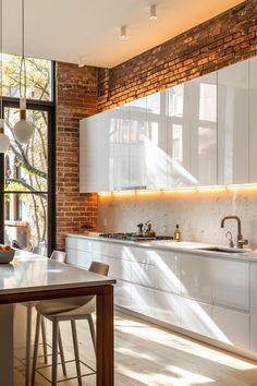 an open kitchen with brick walls and white cabinetry, along with a dining table