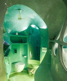 an unusual bathroom with green tiles on the walls and floor, as well as a toilet