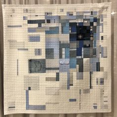 a white quilt with blue and grey squares on it