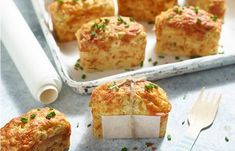 several small muffins are on a tray with a fork and knife next to them