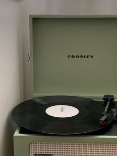 an old record player sitting on top of a green cabinet with the word crosley written on it