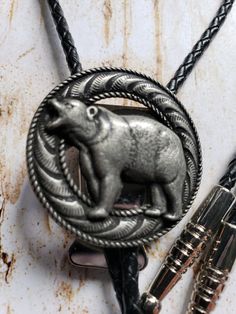 "The bolo tie isn't just for cowboys. It is being worn by presidents to rock stars and actors. They have become a fashion statement with men and women. Our bolos are made with real leather cord, not the inexpensive vinyl or cloth cord. They are 36\" or 40\" long without the tips. The concho is attached to a bolo slide that locks the cord where you want it to stay.The bolo tie is the official neckwear for the states of Arizona, New Mexico, and Texas" Growling Bear, State Of Arizona, Bolo Ties, Hand Tooled Leather, Bolo Tie, Rock Stars, San Antonio Tx, Tie Accessories, Suit And Tie