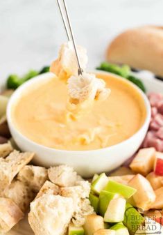 a spoon full of dip being held over a platter of appetizer food