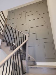 a stair case with metal handrails and decorative wall paneling in a home