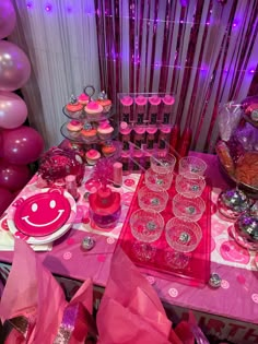 a table topped with lots of pink desserts and cupcakes next to balloons