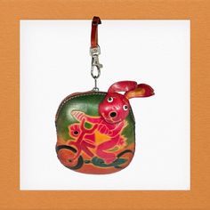 a red and green bag with a rabbit on it's back hanging from a metal hook