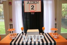 an orange and black table cloth is on top of a basketball themed table with cupcakes