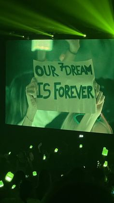 a person holding up a sign that says our dream is forever in front of an audience