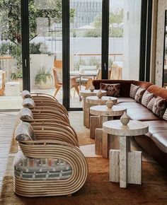 a living room filled with lots of couches and tables in front of large windows