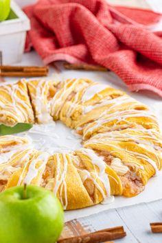 an apple cinnamon roll with icing and cinnamon sticks around it