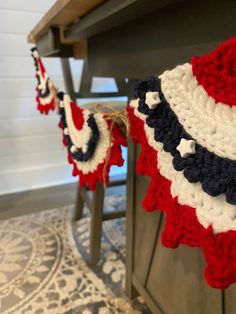 red, white and blue crocheted bunting hanging from a table