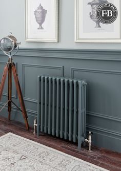 an old fashioned radiator in the corner of a room with two pictures on the wall