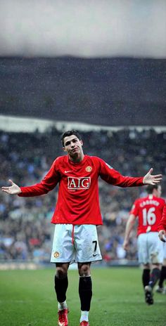 a man standing on top of a soccer field holding his hands out in front of him