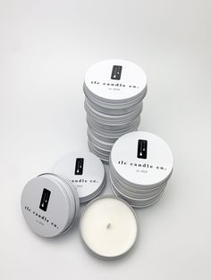 the candles are stacked on top of each other in front of a stack of round tins