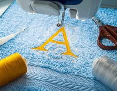 scissors and thread are sitting on a blue towel with the letters a - z in it