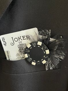 a black suit jacket with a casino chip pin in the pocket and a card on it's lapel