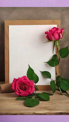 two roses on a table next to an empty card and rolled up paper with leaves