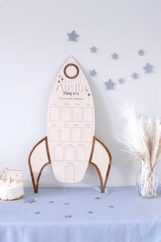 a wooden rocket ship on top of a table next to a vase with feathers in it