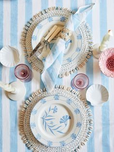 the table is set with blue and white plates, napkins, silverware and candles