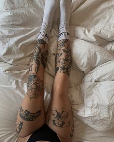 two people laying in bed with tattoos on their arms and legs, both wearing socks