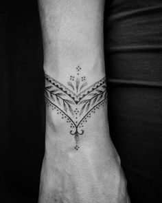 a black and white photo of a wrist tattoo