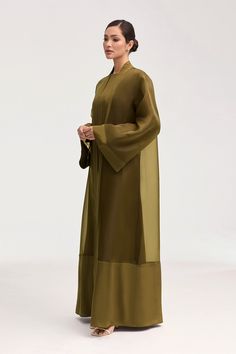 Elevate your wardrobe with the Estee Viscose Open Abaya in Olive Night. Crafted from luxurious viscose, this stunning abaya features elegant flare sleeves and a unique sheer design with solid viscose trim. Breathable and luxurious, this abaya will be your new go-to for sophisticated and exclusive style. Model is 5'7" and is wearing size XS/58". Inner Abaya Dress, Luxury Bollywood Style Maxi Abaya, Organza Abaya Design, Silk Maxi Abaya For Eid, Elegant Abaya With Kimono Sleeves For Eid, Eid Elegant Abaya With Kimono Sleeves, Eid Abaya With Kimono Sleeves And Elegant Style, Elegant Green Maxi Kimono, Elegant Green Maxi-length Kimono