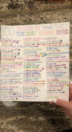 a hand holding up a piece of paper with writing on it that says 100 things to make this the best summer ever