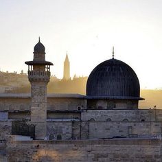 the sun is setting over an old city with towers and minarets in the foreground