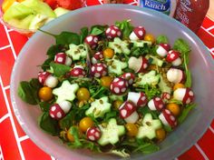 a salad in a bowl on a table next to fruit and ketchup bottles