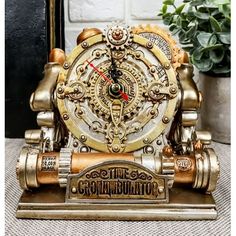 an antique clock is sitting on top of a table next to a potted plant