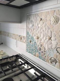 a stove top oven sitting inside of a kitchen next to a wall with seashells on it