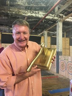 a man holding up a trophy in an unfinished building with other people around him and looking at the camera