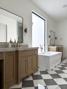 a large bathroom with checkered flooring and two sinks in front of the bathtub