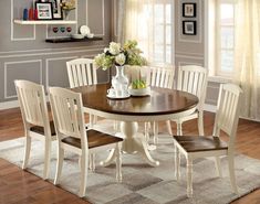 a dining room table with four chairs and a vase on top of it in front of a window