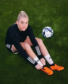 a woman is sitting on the grass with her soccer ball