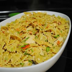 a white bowl filled with pasta and veggies on top of a stovetop