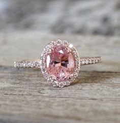 an engagement ring with a pink diamond in the center on top of a piece of wood