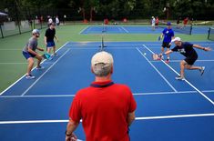 a group of people playing tennis on a blue court